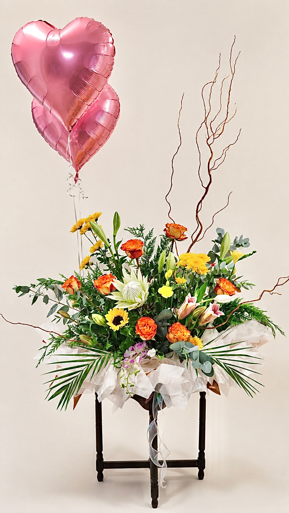 Colourful celebration floral arrangement with pink heart balloon and seasonal flowers