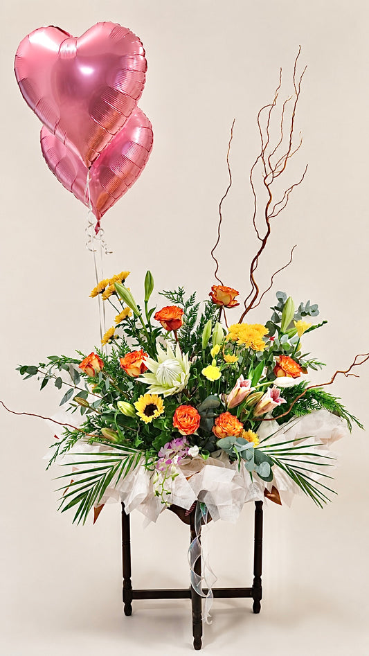 Colourful celebration floral arrangement with pink heart balloon and seasonal flowers
